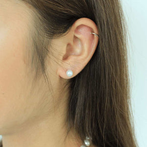 woman wearing pearl button earrings