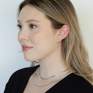 woman wearing sterling silver rhodium plated double cz huggie earrings